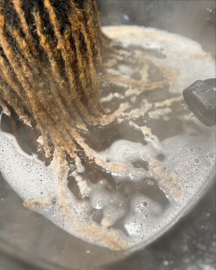 Locs soaking in a basin of lathered water during a wash